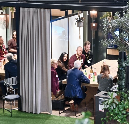 Group of diverse professionals from Nedonboard engaging in lively conversation while dining at a vibrant restaurant