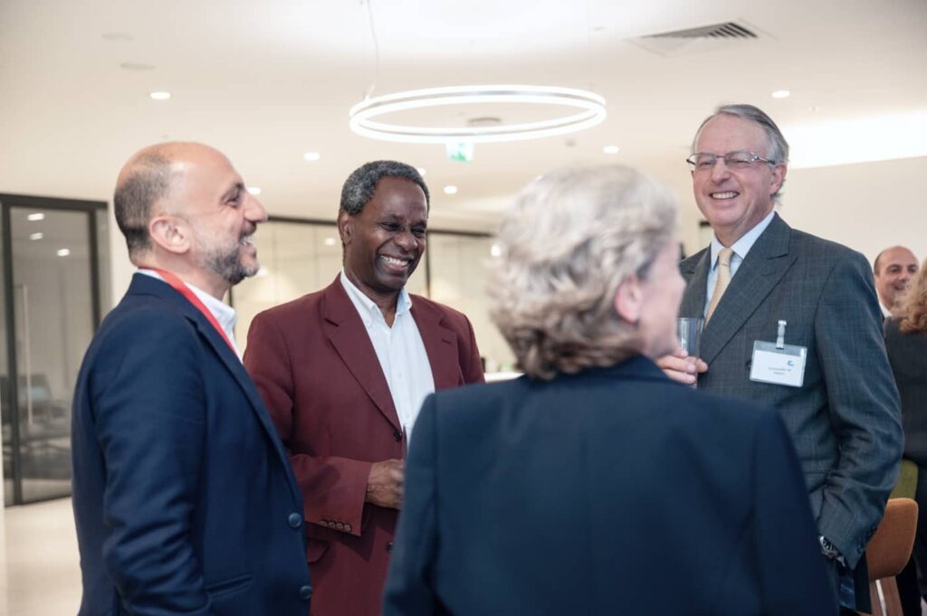 At a Nedonboard conference, three men in suits deeply engaged in conversation, exchanging ideas and opinions on corporate governance strategies.